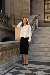 a lady in a white crop jacket and a black long skirt